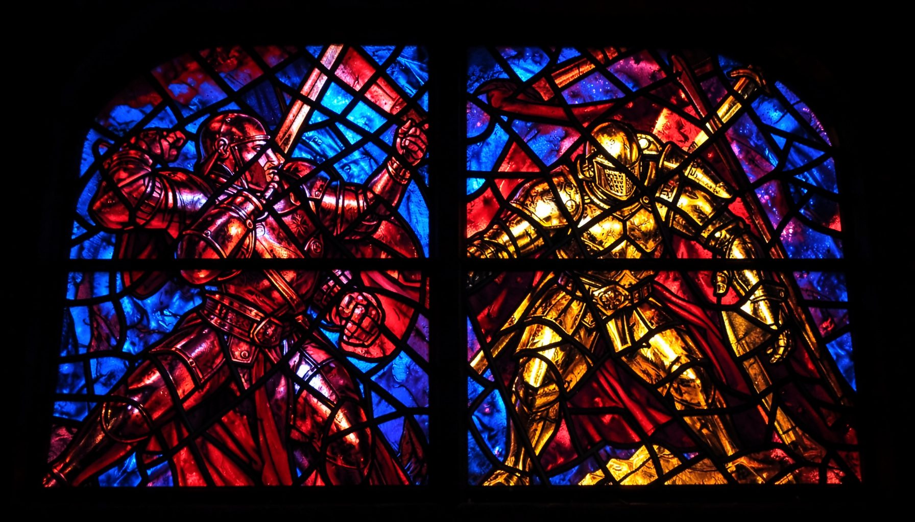 A dramatic stained-glass composition with bold leaded segments depicting armored fighters in combat, rich ruby reds, deep cobalt blues, and amber golds glowing against dark iron frames.
